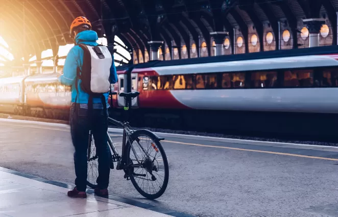 Man next to bicycle in front of a train 